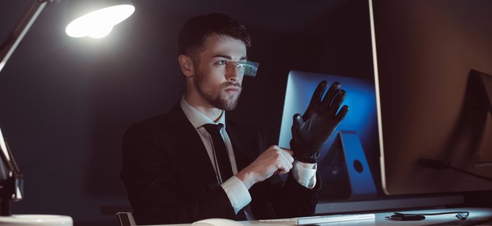 Porträt eines Ermittlers, der Handschuhe trägt und auf einen Computerbildschirm auf einem Schreibtisch blickt