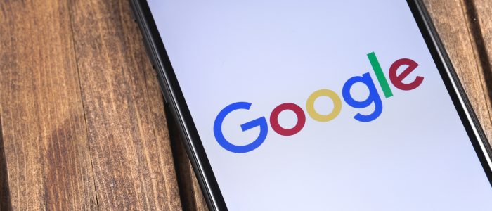 Auf einem Holztisch liegt ein Smartphone mit Google-Logo