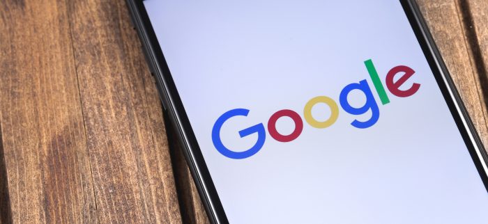 Auf einem Holztisch liegt ein Smartphone mit Google-Logo