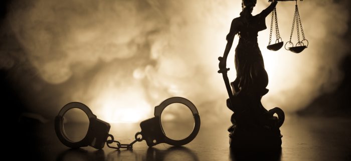 Silhouette von Handschellen mit der Justizstatue auf nebligem Hintergrund