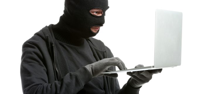 Ein männlicher Hacker mit Maske und einem Laptop