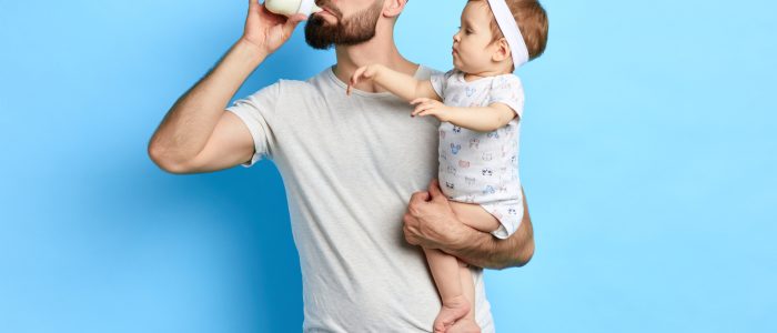 Junger Vater trinkt Milch aus dem Fläschchen seiner kleinen Tochter