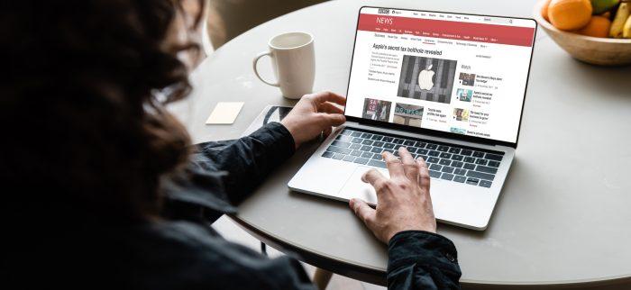 Rückenansicht eines Lesers, der einen Laptop mit BBC-Nachrichten und Apple-Logo auf dem Bildschirm