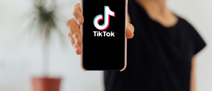 TikTok-App auf dem Display eines Mobiltelefons in der Hand einer Frau