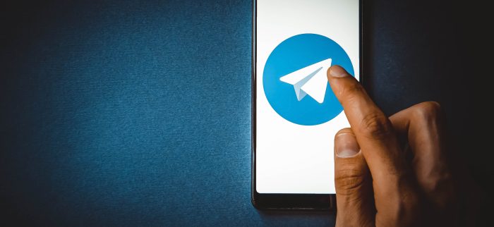 Ein Mobiltelefon auf blauem Hintergrund mit dem Logo des Messengers Telegram