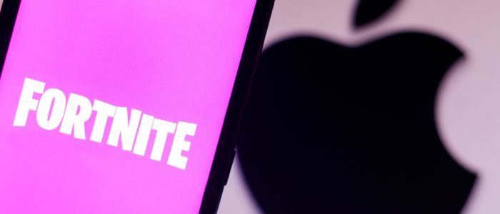 Das Fortnite-Logo auf einem Smartphone mit dem Apple-Logo im Hintergrund