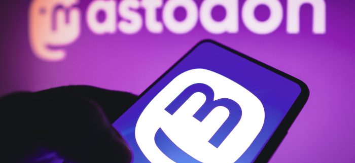 Mastodon Icon auf einem Handy, vor einem Mastodon Logo