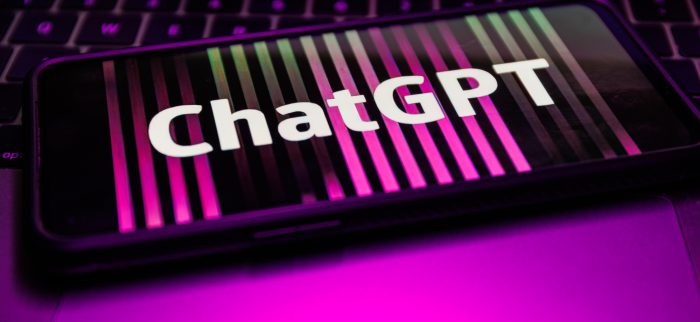 Ein Smartphone mit dem Schriftzug "ChatGPT" liegt auf einem Laptop