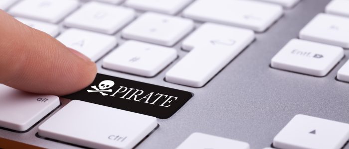 Ein Finger drückt eine schwarze Piratentaste auf einer Tastatur