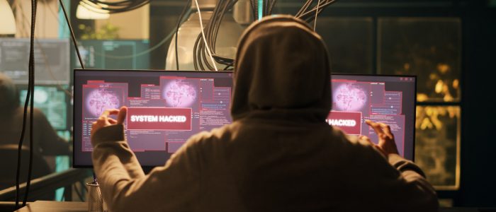 Ein junger Hacker sitzt vor seinen beiden Monitoren