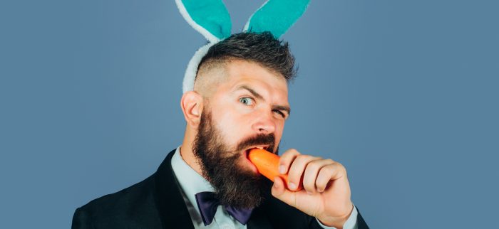 Karotte essender Mann mit Kaninchenohren