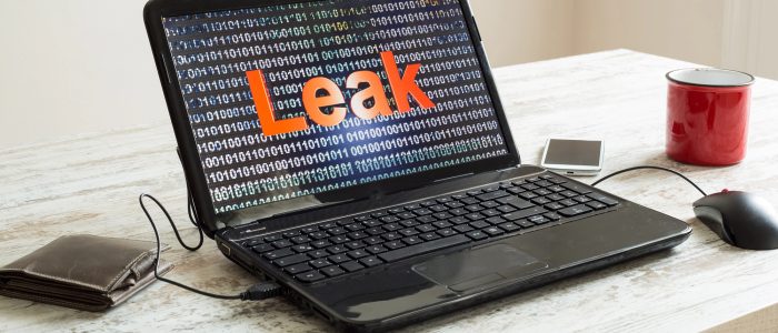 Ein Laptop steht auf einem Tisch und zeigt das Wort "Leak" vor Binärcode