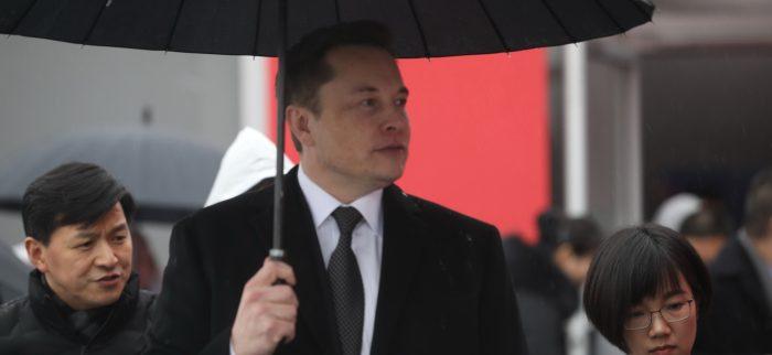 Elon Musk mit einem schwarzen Regenschirm
