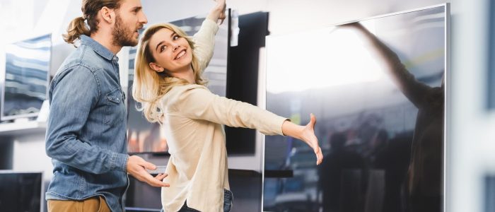 Junges Paar bewundert einen großen Fernseher