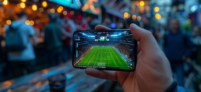 Eine Person hält ein Smartphone hoch, auf dem ein Fußballspiel live gestreamt wird