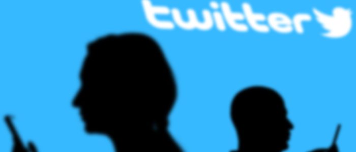 Schatten zweier Smartphone-Nutzer mit Twitter-Logo im Hintergrund