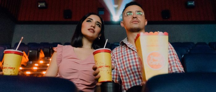 Ein Paar sitzt im Kino mit Popcorn und Getränk.