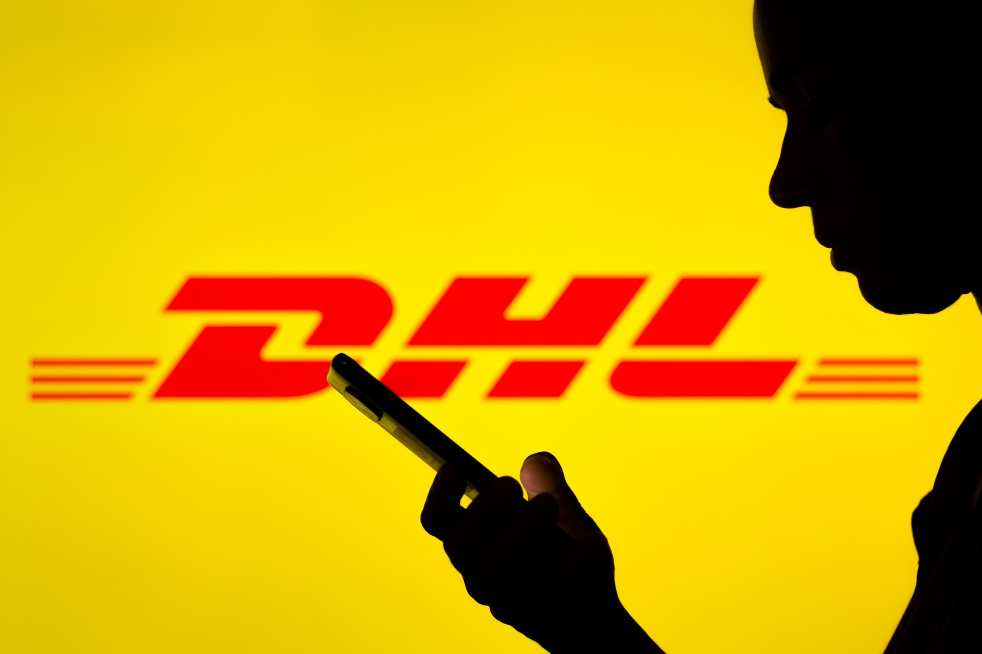 Schatten eines Mannes, der auf sein Smartphone schaut, im Hintergrund das DHL Logo