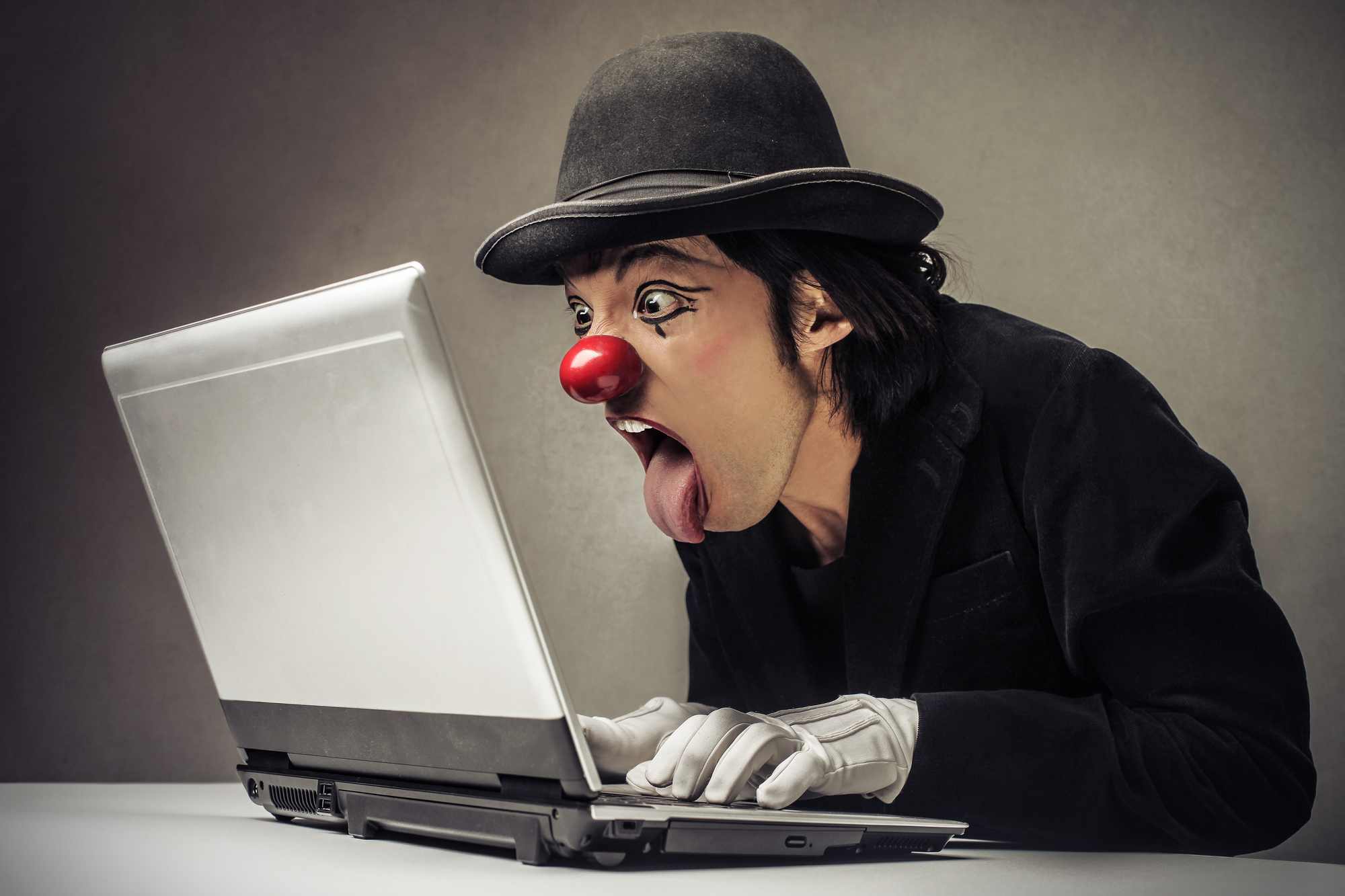 Ein staunender Clown sitzt vor einem Laptop und liest die Glosse