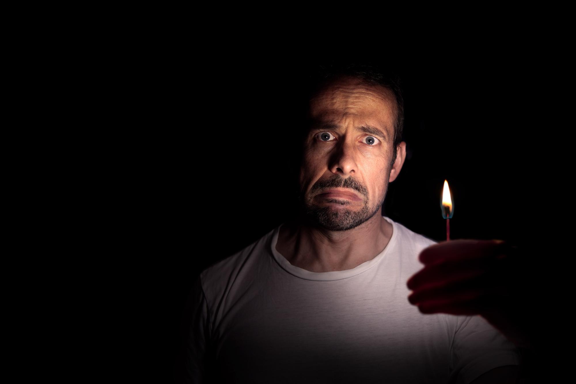 Ein Mann mit einer Kerze in der Dunkelheit