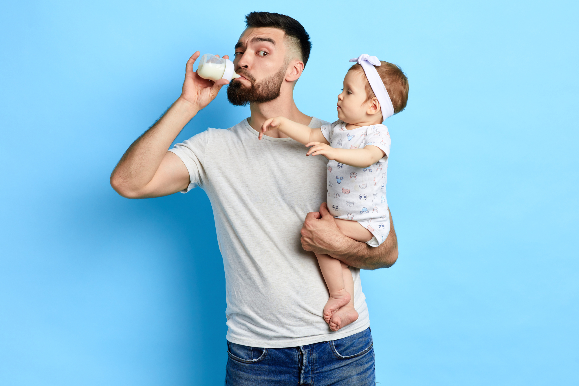 Junger Vater trinkt Milch aus dem Fläschchen seiner kleinen Tochter