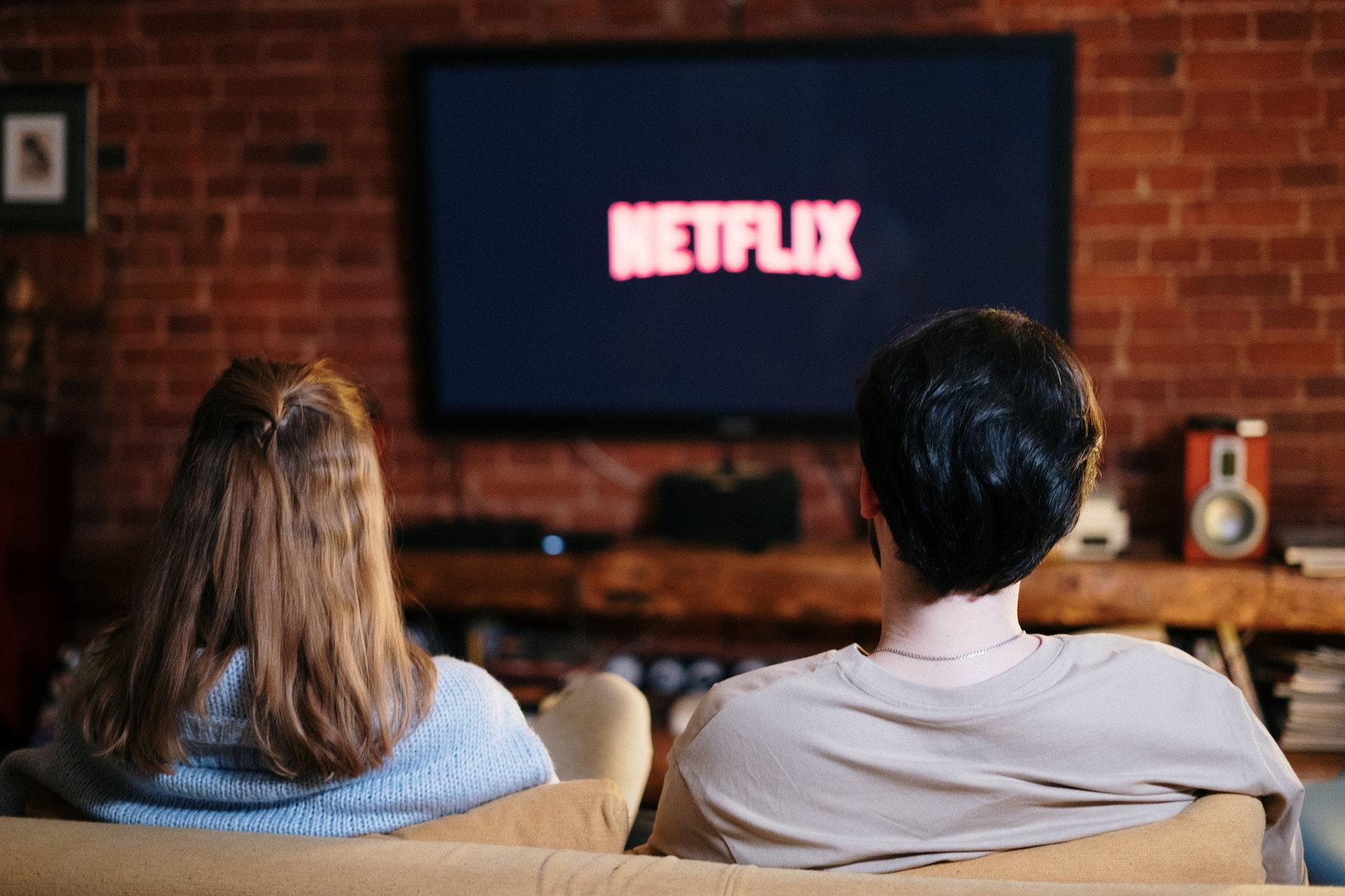 Ein Paar sitzt vor einem Fernseher mit Netflix-Logo