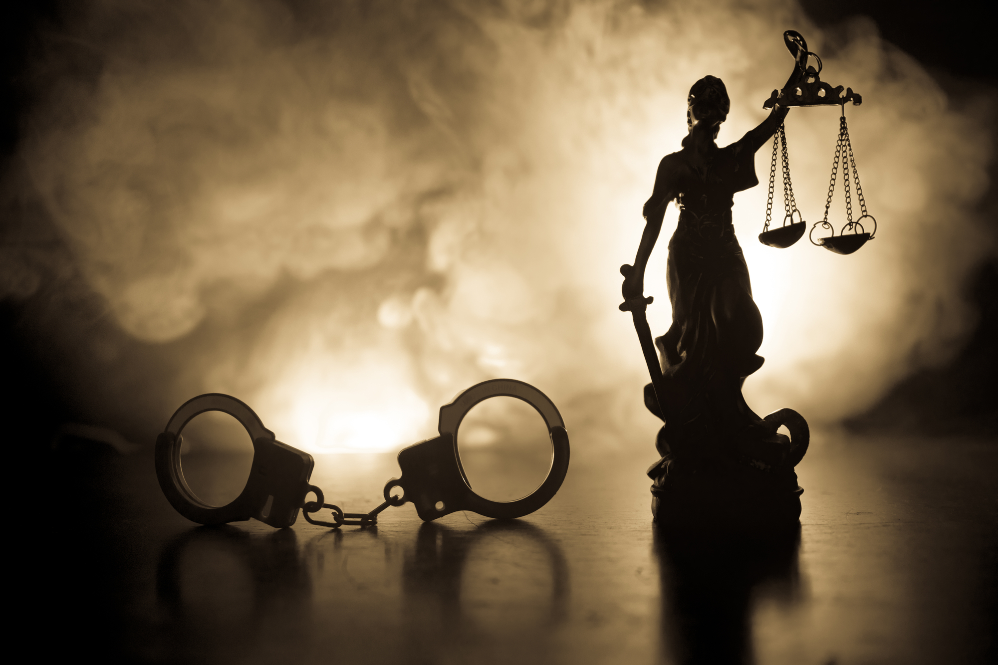 Silhouette von Handschellen mit der Justizstatue auf nebligem Hintergrund